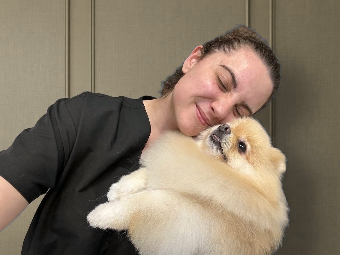 Lucía abrazando con cariño a un pomerania crema recién arreglado