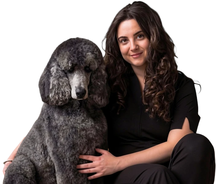 Lucía, peluquera canina de Lu.Groom, sentada junto a un caniche gigante gris recién arreglado